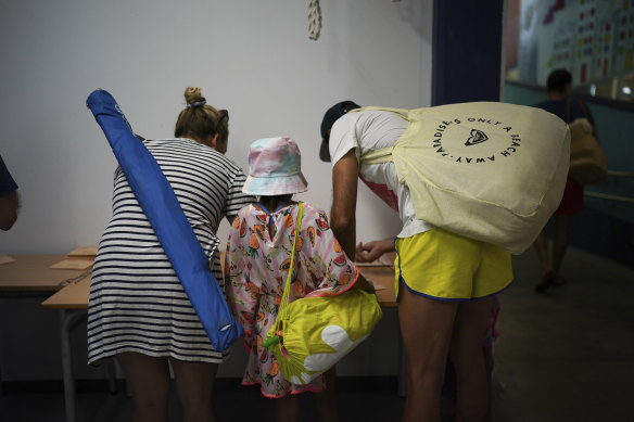 A family carrying things for the beach prepare their ballots at a polling station in Badalona, on the outskirts of Barcelona, on Sunday.