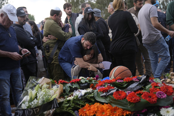 Family and friends of Alon Shamriz, 26, mourn over his grave during his funeral in the cemetery of Kibbutz Shefayim, southern Israel, Sunday Dec. 17, 2023. Shamriz was one of three hostages mistakenly shot to death by Israeli troops Friday in a battle-torn neighborhood of Gaza City. 