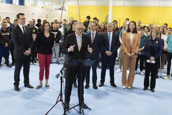 Prime Minister Anthony Albanese addresses the press as Cate Campbell (orange suit) and others look on.