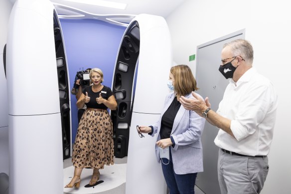 Labor candidate for Leichhardt Elida Faith stands inside a 3D mole mapping machine in Cairns, watched by Senator Nita Green and Opposition Leader Anthony Albanese.