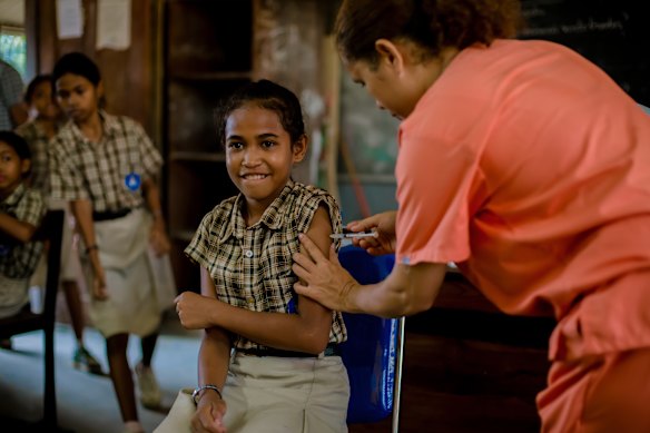 School student Nofelia Maia da Costa Belo Lopes (centre) receives the HPV vaccination at the Rumbia Primary school in Dili.