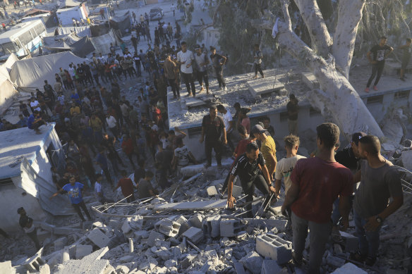 Palestinians search for bodies and survivors in the rubble of a residential building destroyed in an Israeli airstrike.