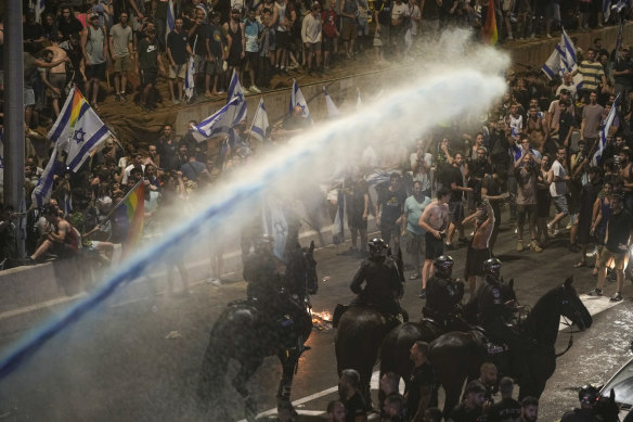 Riot police tries to clear demonstrators with a water cannon during a protest against plans by Netanyahu’s government to overhaul the judicial system, in Tel Aviv.