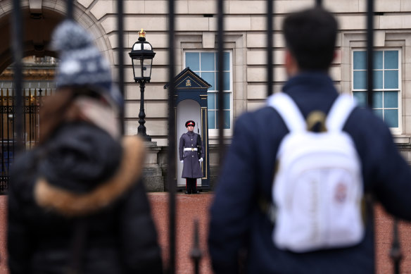 A Scottish Guard outside of Buckingham Palace on February 20, 2022 in London, England, as well-wishers for the Queen look on.