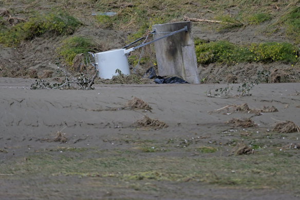 A fuel tank is half buried in silt in a field on Dartmoore Road following flooding on February 16 in Napier, New Zealand. 