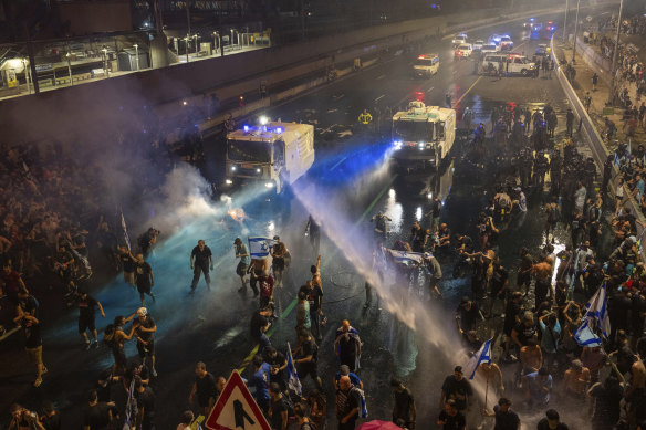 Riot police tries to clear demonstrators with a water cannon during a protest against plans by Netanyahu’s government to overhaul the judicial system, in Tel Aviv.