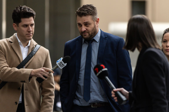 Sam Fisher (centre) arrives to questions from reporters at the County Court of Victoria in Melbourne.