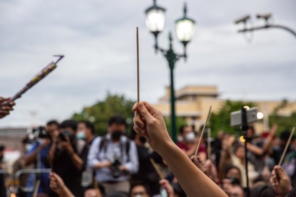 Anti-government protesters wave chopsticks as makeshift wands to "Cast the Patronus Charm to Protect Democracy" in Bangkok on Monday.
