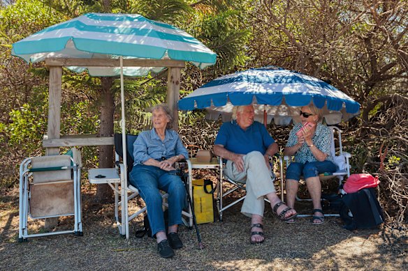 Locals seek shelter in a shaded breezy spot in the Narrabeen Beach car park.