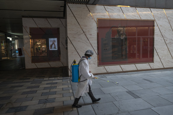  worker disinfects the walkway near closed shops in the usually bustling Taikoo Li mall after many retail stores were closed to help prevent the spread of COVID-19 