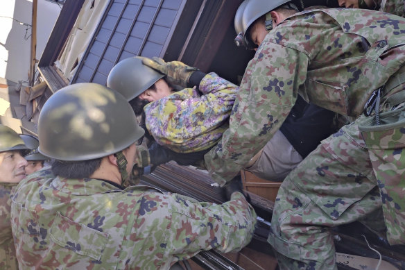 Japanese Self Defence Force members carry an injured person out of a collapsed house, following strong earthquakes in Wajima, Ishikawa prefecture.