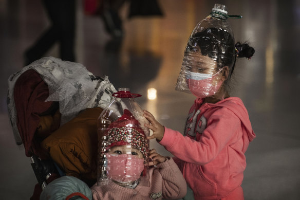 Chinese children wear plastic bottles as protective masks while waiting to check in to a flight in Beijing.