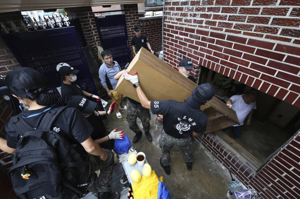Soldiers carry debris after floodwaters drained from a submerged house following heavy rains in Seoul.
