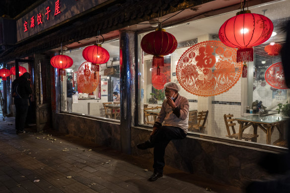 A cook smokes outside a nearly empty restaurant after local authorities allowed restaurants to re-open in Beijing.