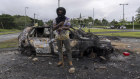 A man stands in front a burnt car after unrest in Noumea, New Caledonia this week.