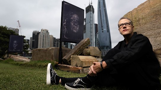 Artist, Brenda Croft, with a detail from her installation “Naabama (thou shall/will see): Barangaroo (army of me)” which features 60 large portraits of First Nations women and children along the Barangaroo waterfront in Sydney. 