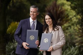 California Gov. Gavin Newsom and New Zealand Prime Minister Jacinda Ardern pose with agreements they signed in San Francisco.