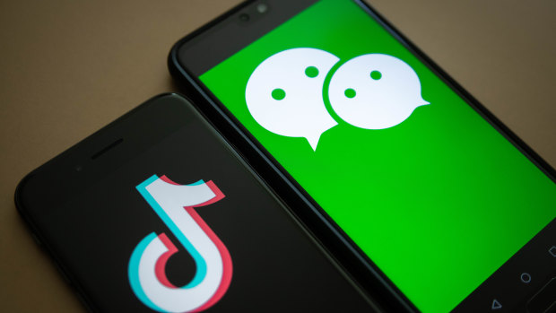 The logo for Tencent Holdings' WeChat app, right, and the logo for ByteDance's TikTok app on a phone. 
