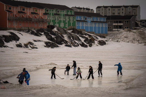 Children play ice hockey on a pond in Nuuk, Greenland.
