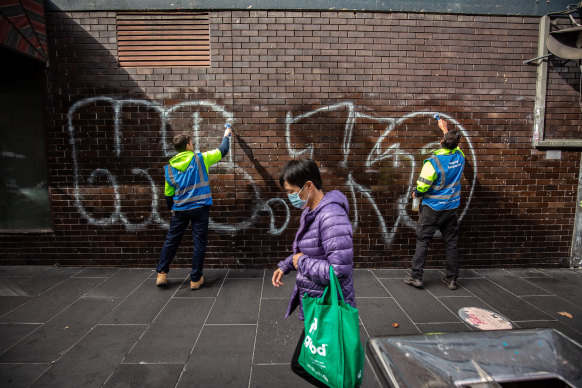 Hugh Cox and Ben Ivory clean off  tagging graffiti on a wall near the corner of Little Bourke and Russell streets. 