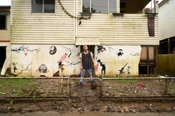 Eli Roth stands outside his flood-affected house in Lismore as he clears mud and debris from a drain on Tuesday morning.