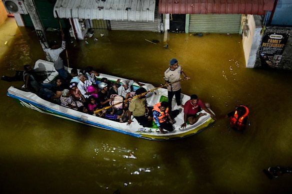 People ride on a boat belonging to Sri Lanka’s army on a flooded street after heavy rainfall in Wellampitiya on the outskirts of Colombo yesterday.