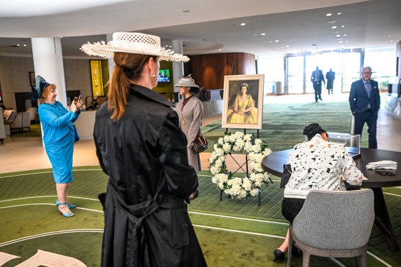 Racegoers sign a condolence book at Flemington racecourse. 