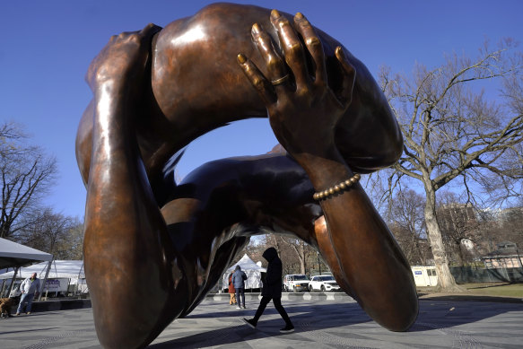 A passer-by walks under the 6.7-metre-high bronze sculpture “The Embrace,” a memorial to Dr Martin Luther King jnr and Coretta Scott King, in the Boston Common.