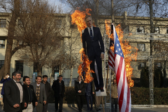 Pro-government protesters burn an American flag and a cut-out depicting British ambassador Rob Macaire.
