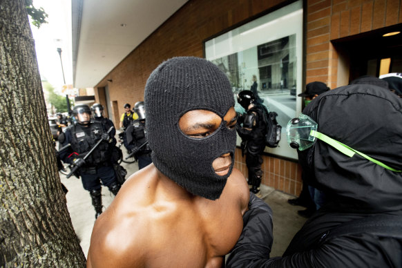 A protester against right-wing demonstrators walks away from a police line following in Portland.