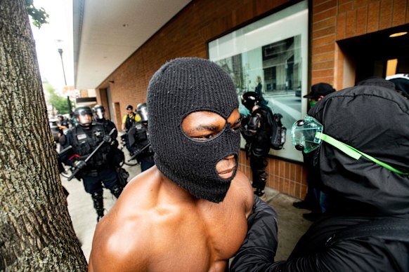 A protester against right-wing demonstrators walks away from a police line following in Portland.