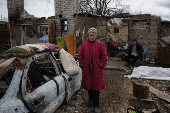 Iryna, 56, stands in front of her destroyed house in the village of Lukashivka.