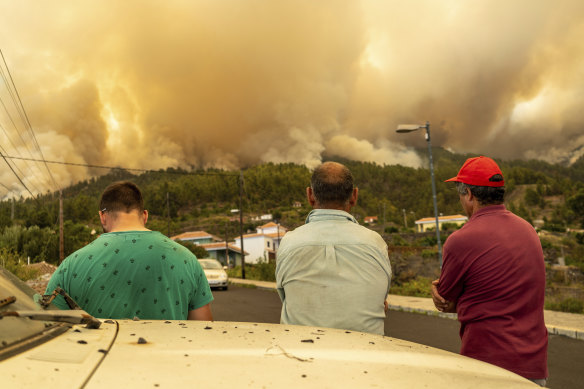 Local residents look on at a burning forest fire, near Puntagorda on the Canary Island of La Palma, on Saturday, July 15.