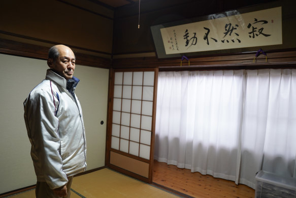 Yasuhisa Arishima, the head priest of Itsukushima shrine, in front of a calligraphy painting by Shinzo Abe. 