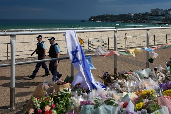 Police patrolling Bondi Beach near tributes to those killed and injured in the shooting.