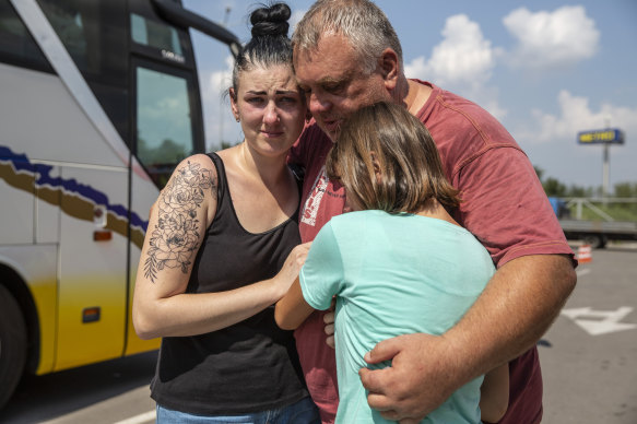 Serhil Ardolyanova, 54, embraces his daughters, Inna, 31, and Masha, 10, before they depart on an evacuation bus at a humanitarian aid center for internally displaced people in Zaporizhzhia, Ukraine.