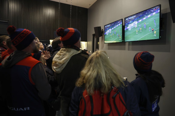 Footy fans in an MCG bar watch the Matildas after play was shut off on the big screens.