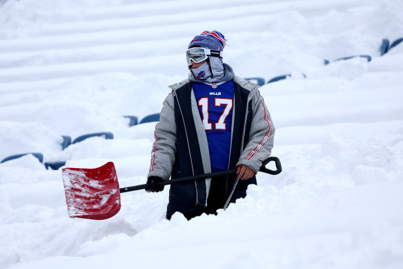 A person clears snow from the stand at the Buffalo Bills’ NFL stadium.