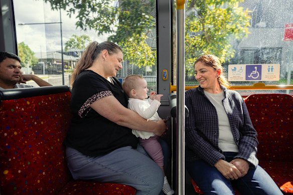 Macarthur Heights residents Antonella Panozzo and her daughter Ruby, 11 months, travel on the new bus with local Veenu Chawlla.