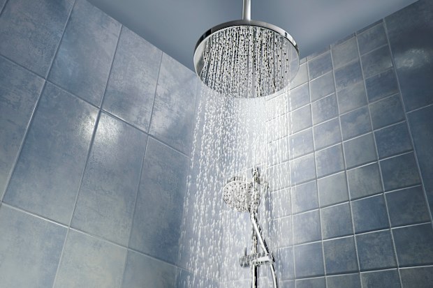 Low angle of running water from shower head in a cool coloured shower.