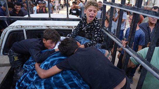 Palestinians children mourn over the body of their father, Mohammed Ghaben, who was killed while heading to an aid distribution hub, in Gaza City.