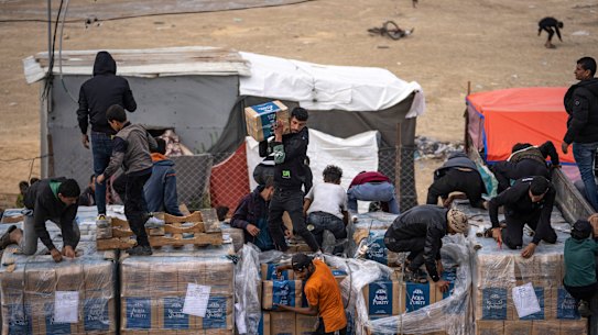 Palestinians climb onto a humanitarian aid truck after it crossed into the Gaza Strip in Rafah.
