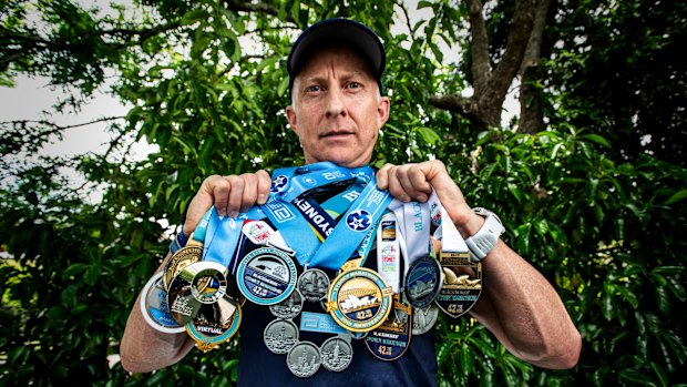 Mark Goodwin with his medals from years of competing in the Sydney Marathon, and his medal for finishing every major in the world.