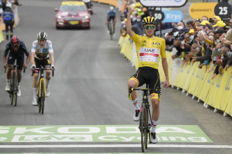 Tadej Pogacar, wearing the overall leader’s yellow jersey, celebrates as he crosses the finish line. 