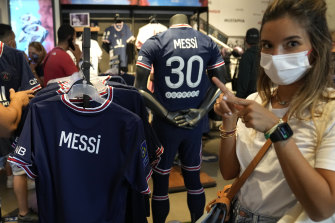 A PSG fan poses with the Argentine star’s new shirt at the club’s official store.