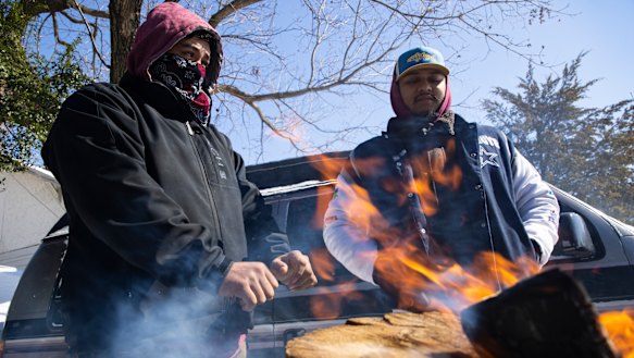 Brothers Alfredo Colon, left, and Eduardo Colon chat over a fire in front of their East Dallas homes after the family lost their power.