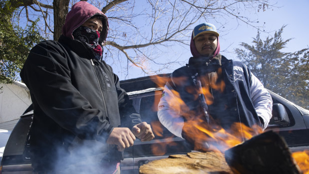 Brothers Alfredo Colon, left, and Eduardo Colon chat over a fire in front of their East Dallas homes after the family lost their power.