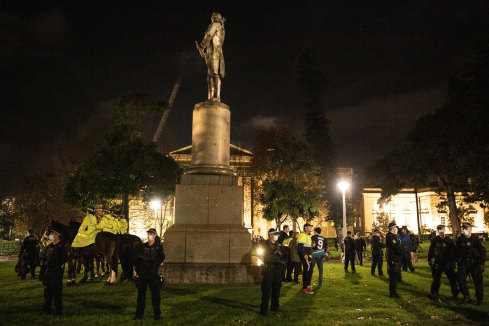 Police guard a statue of Captain James Cook in Hyde Park on Friday night. It was defaced on Sunday morning but immediately restored.