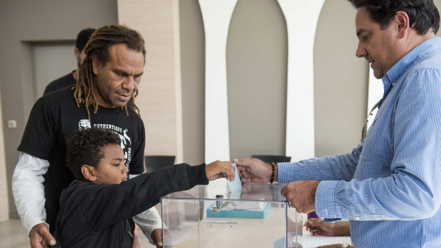 A boy helps his father to vote in New Caledonia's second independence referendum. 
