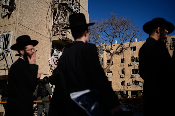 يبدو الناس ينظرون إلى المباني السكنية التي تضررت بفعل هجوم صاروخي إيراني في أراد، جنوب إسرائيل، يوم الأحد.